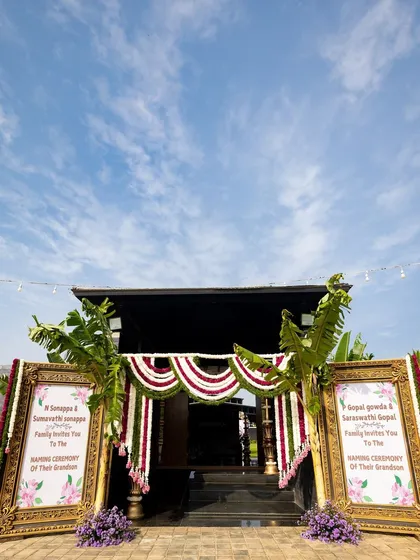A grand welcome for a grand celebration. For this naming ceremony, I framed the entrance with large, ornate golden frames displaying the invitation, complemented by banana leaves and fresh flower garlands for an authentic South Indian welcome.
