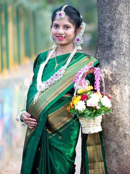 A beautiful portrait of the mom-to-be at her baby shower. Holding a basket of flowers, she is adorned in a traditional green saree and floral jewelry, ready for the ceremony.