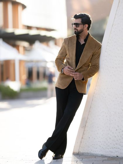The mustard velvet blazer offers a lean, stylish silhouette, shown here against a modern, urban backdrop.