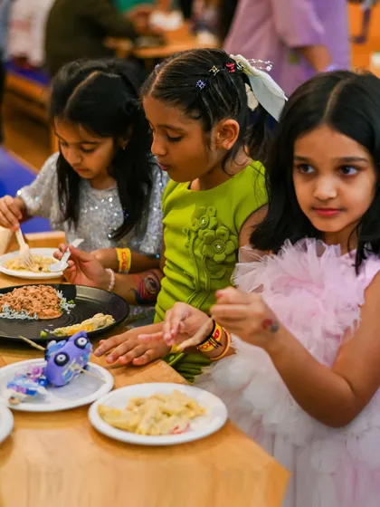Friends enjoying a meal of pasta and other treats during a birthday party. We serve food that kids love to eat.