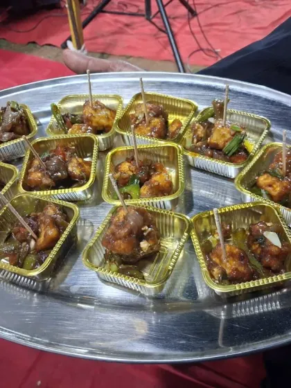A tray of spicy Chili Paneer starters, served in individual gold foil cups with toothpicks for easy eating.