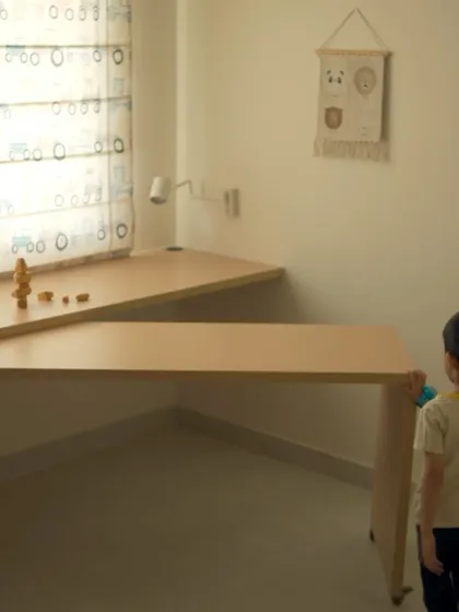 This image shows a clever, openable study desk in a child's room. The desk can be folded away to create more play space, demonstrating a focus on multi-functional design.
