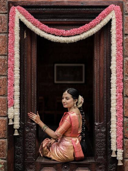 A beautiful portrait of the bride framed by the doorway and flower garlands. Her makeup is soft and traditional, perfect for this classic wedding shot.