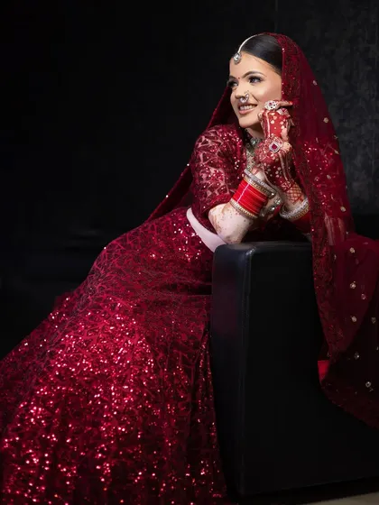 A full-length shot of a bride in a sparkling red sequin lehenga. The makeup is glamorous yet elegant, designed to complement the dazzling outfit and make her shine on her special day.