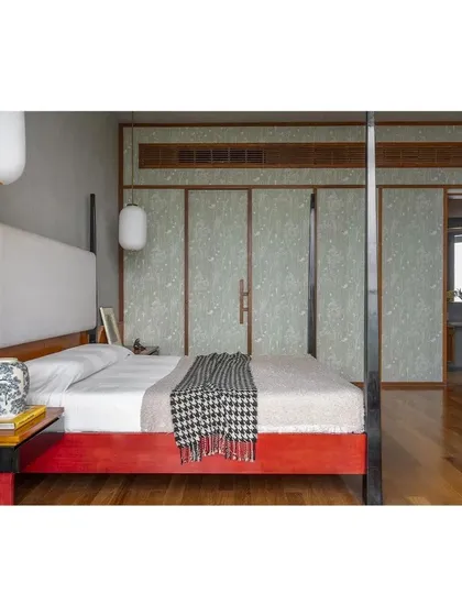 This custom four-poster bed, with its vibrant red lacquered wood base, was inspired by the client's roots and the traditional craft of Channapatna toys. Paired with serene, textured wallpaper panels and warm teak flooring, it becomes the centerpiece of a deeply personal and culturally rich bedroom.