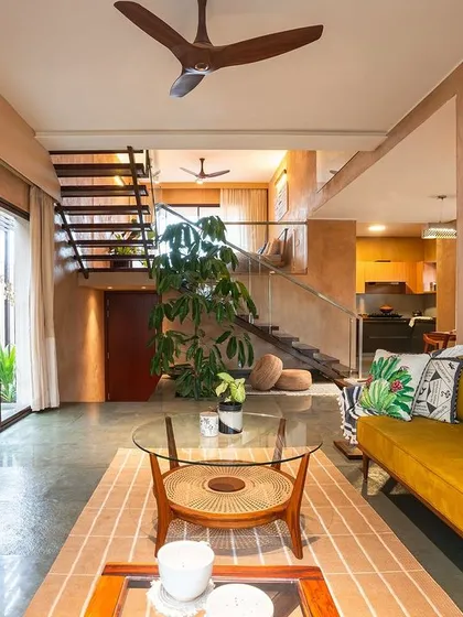 Another view of the living area, showing the connection to the upper level via a minimalist staircase. The large, hand-painted artwork adds a burst of tropical color, contrasting beautifully with the neutral tones of the room.