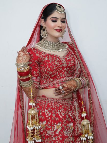 The quintessential bridal pose. Her makeup features a classic red lip and softly defined eyes, perfect for her red lehenga.
