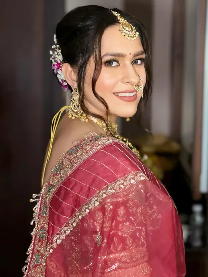 A beautiful bride in a deep red saree, ready for her ceremony. I created a soft, messy updo with fresh flowers and focused on glowing skin and defined eyes for her makeup.