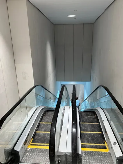 A view down the newly installed escalator, showing the clean lines of the stone-cladded walls. This is an example of the precise execution required for integrating major structural elements into the design.