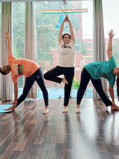 Students practice Vrikshasana (Tree Pose) and Trikonasana (Triangle Pose) together in our sunlit studio.