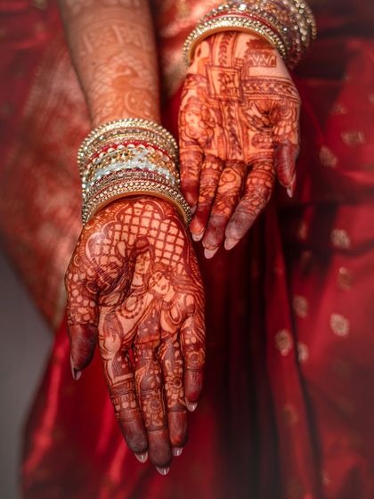 A beautiful photograph of the bride's hands, showcasing the intricate and artistic henna design, an essential part of the Indian bridal tradition.
