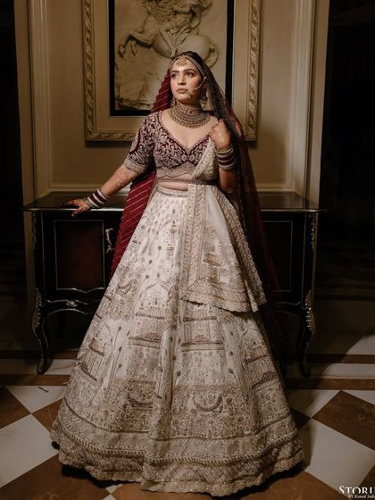 A full-length portrait of the bride, Niesha, standing beside a classic piece of furniture, exuding royal elegance.