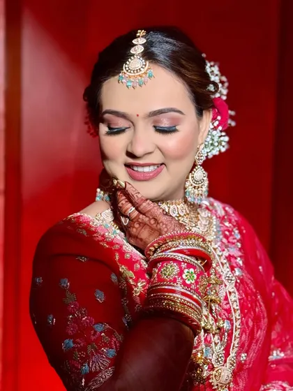 Draped in red, glowing with grace. This bride's smile says it all. The soft glam makeup with a floral bun creates a look of pure poetry.