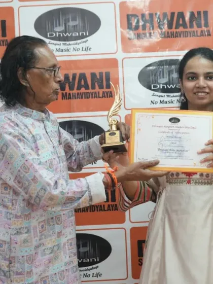 A senior guru presents an award to an adult student.