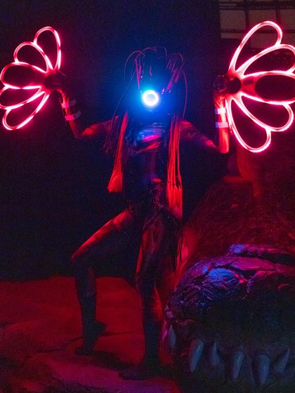 The Alien performer illuminated by red light in a dark environment. This demonstrates how our LED shows create a powerful visual impact even in low-light settings.