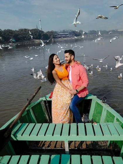 Capturing the full scene at Yamuna Ghat, this shot shows the couple surrounded by nature and the iconic birds of the location.