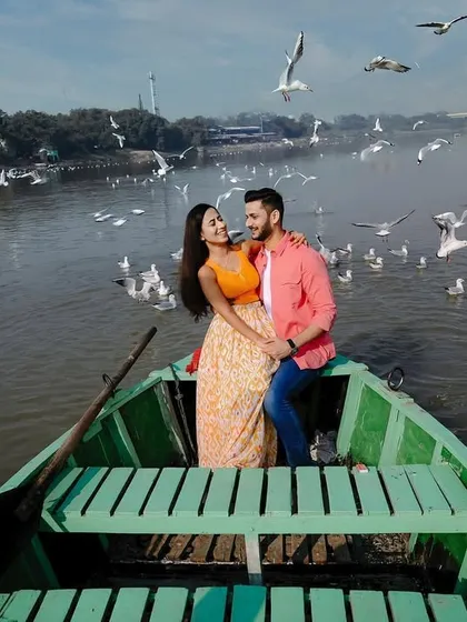 A wide shot showing the couple surrounded by a huge flock of birds on the Yamuna river. This image captures the incredible atmosphere of this popular Delhi pre-wedding shoot location.