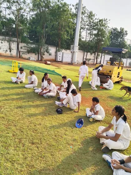 Young female cricketers resting between drills, sharing a moment of camaraderie at the Chinchwad ground.