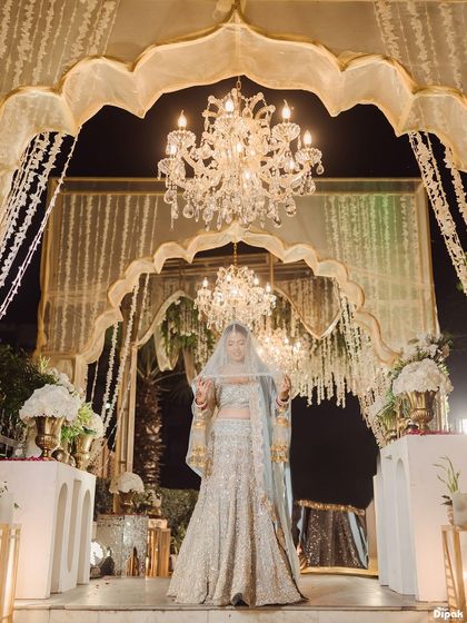 The bride stands beneath a canopy of cascading flowers and crystal chandeliers, a vision of pure elegance. I use the opulent decor and dramatic lighting of the venue to frame her, creating a portrait that feels both grand and deeply personal.