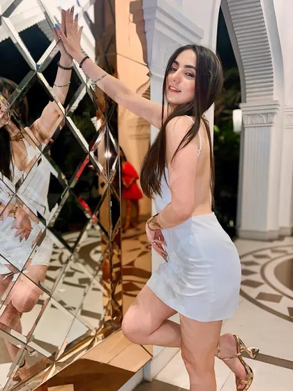 Playing with reflections in a short white backless dress. This adds a creative and glamorous touch to the photo.