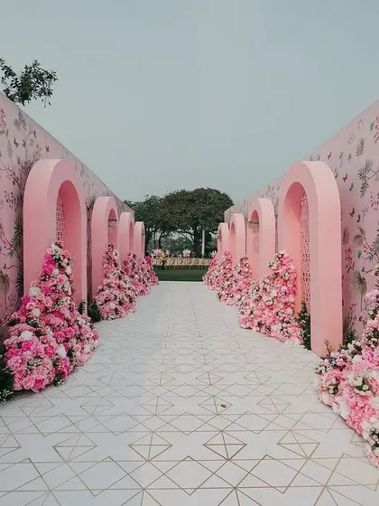 The grand entrance walkway for Yasha and Rahil's wedding. We designed a tunnel of blush pink arches, lined with cascading flowers and set against a custom floral wallpaper, to give guests an enchanting welcome.