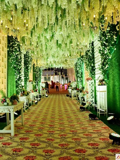 An enchanting walkway where the ceiling is a dense canopy of hanging white and green wisteria. This immersive entrance makes guests feel like they are walking through a magical forest.