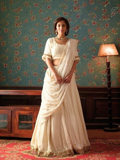 This elegant off-white lehenga with a draped dupatta is a timeless and graceful choice. It is perfect for a guest who wants to look chic and understated.