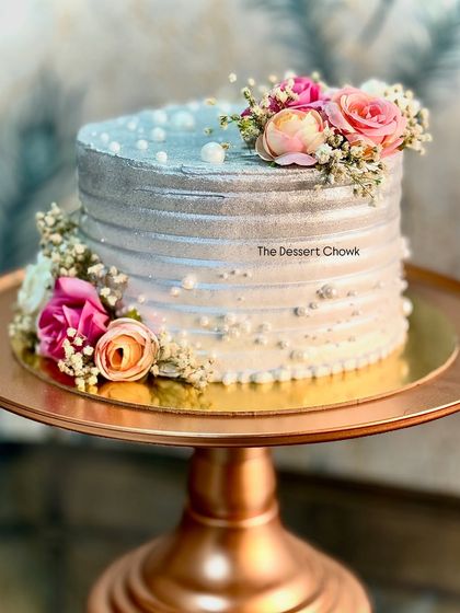 For a 25th wedding anniversary, I designed this stunning silver-dusted tall cake adorned with fresh flowers. The metallic sheen gives it a sophisticated look, perfect for celebrating a silver jubilee.