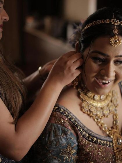 A candid moment during the getting-ready process. This shot captures the joy of the bride and the final touches being put on her hair and jewelry, showing the complete bridal look.