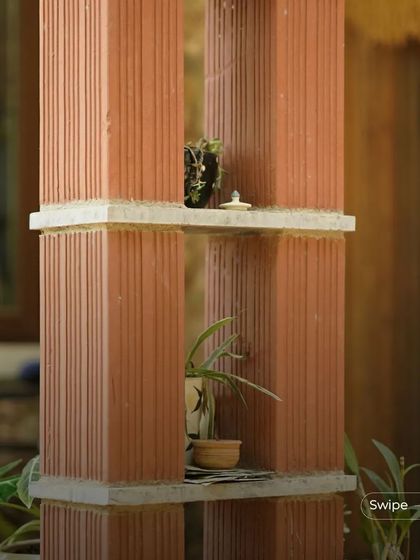 Terracotta pillars used as shelving for small plants and decor, demonstrating a creative and integrated use of architectural elements.