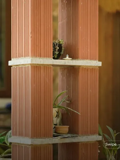 Terracotta pillars used as shelving for small plants and decor, demonstrating a creative and integrated use of architectural elements.