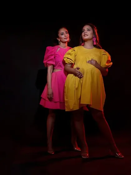 A creative studio shot featuring two models in contrasting pink and yellow dresses, creating a visually interesting and colorful composition.