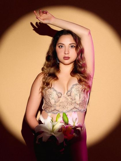A creative floral portrait using a spotlight to frame the model, who is holding a bouquet of lilies.