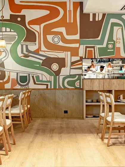 We collaborate with restaurants and cafes to create an ambiance that tells their brand's story. This abstract, flowing mural for 'Blanca' in Delhi was designed to complement the fine-dining experience, using a palette of earthy greens and browns to create a sophisticated yet organic backdrop for the open kitchen.