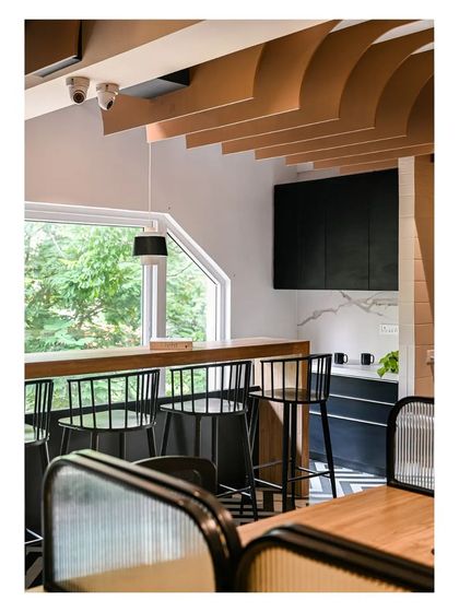 The compact pantry and dining area feature a high-top counter with bar stools, overlooking a large window. The design is simple, functional, and bright.