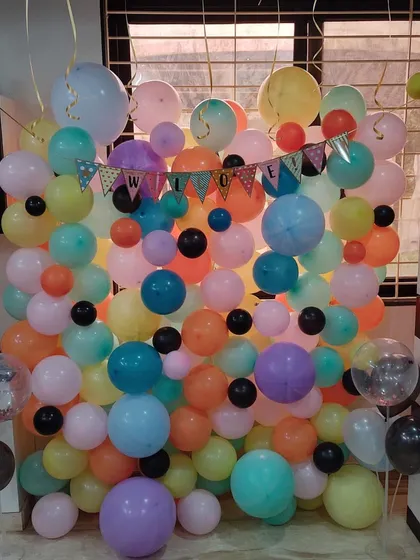 A balloon wall is a fantastic way to create a fun and colorful photo backdrop for any event. This welcome party setup uses a vibrant mix of pastel and bright balloons to build a dense, eye-catching feature wall.