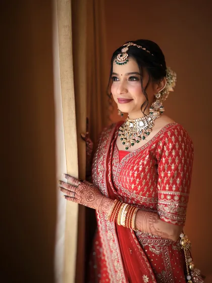 A timeless moment for a classic North Indian bride. This look is all about soft glam, with a flawless base and defined eyes that complement her elegant red lehenga.