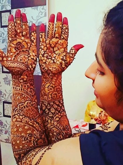 The bride admiring her intricate henna. This design is packed with detail, from the tips of her fingers to her elbows, ensuring she looks perfect from every angle.