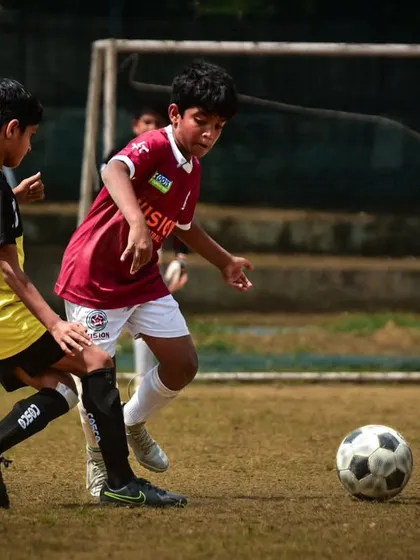 A player dribbles towards the goal, fending off a challenge. We train our players to be strong on the ball and composed under pressure.