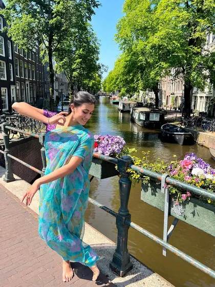 Posing in a delicate floral saree on a bridge over an Amsterdam canal. This shot showcases how traditional Indian wear can be styled beautifully in an international, contemporary context.
