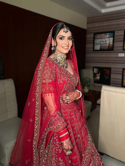 The full view of this timeless bridal look, where the makeup perfectly complements the Kundan jewelry and the rich red lehenga.