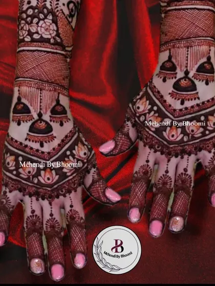 A beautiful back-hand design featuring hanging jhumka motifs. The pattern creates a V-shape that elongates the hands, and the mix of bold and delicate work is very eye-catching.