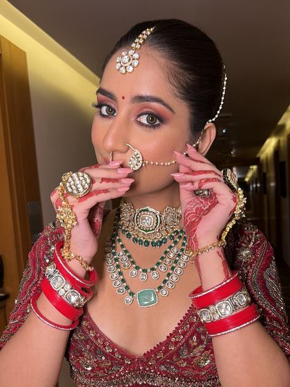A close-up of the bride adjusting her nath. The makeup is kept soft and glowing to let the vibrant colors of her outfit and her beautiful smile shine.