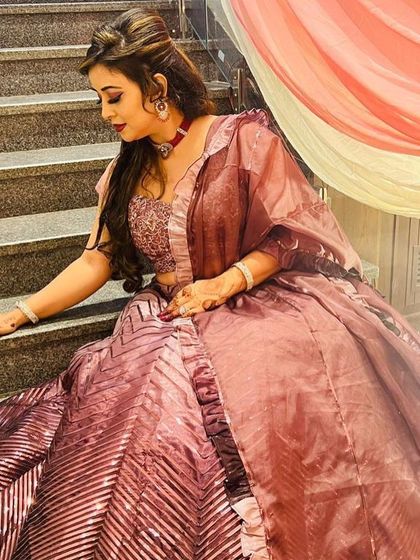 An elegant seated pose showing the flow and shimmer of the wine-colored lehenga. It's a comfortable yet glamorous option for a long evening of celebrations.