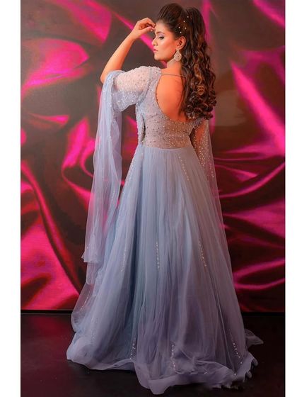 A back view of this enchanting powder blue gown. The open back and flowing cape sleeves add a touch of modern elegance and fairytale charm.