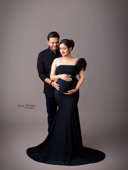 A smiling couple enjoying a moment during their studio maternity session. The simple black outfits keep the focus on their happy connection.