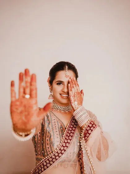 A playful peek-a-boo moment showing off the intricate henna design. This shot captures the bride's happy and shy personality, a beautiful unscripted moment before the main event.