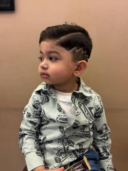 An adorable and stylish haircut for a little boy, featuring a creative design on the side.