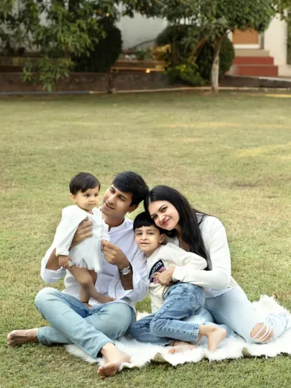 A happy family of four enjoying a picnic-style photoshoot in the park, capturing their relaxed and joyful connection.
