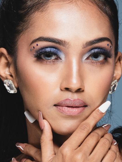 A captivating beauty headshot with a direct gaze. The small rhinestones near the eye add a creative touch to the glamorous makeup.